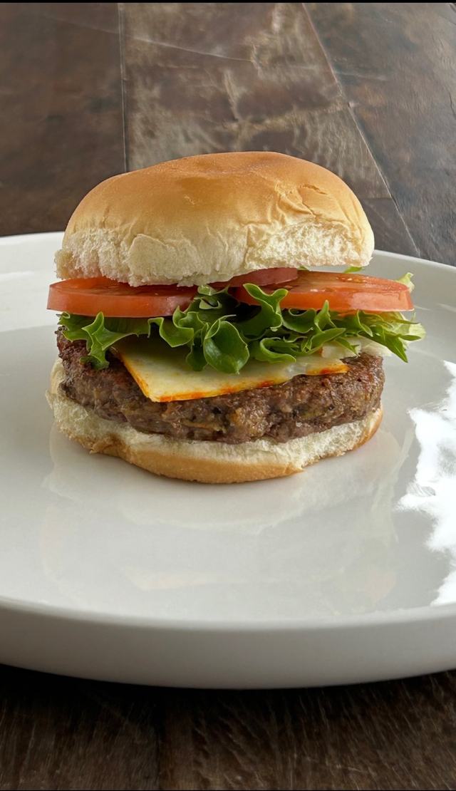A cheeseburger with lettuce and tomato on a white plate