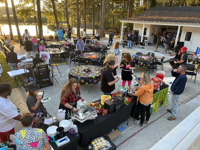 Guests at an outdoor lakeside party serving themselves from a catered buffet